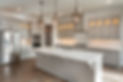 A spacious kitchen featuring light grey shaker cabinets, a large central island with a white quartz worktop