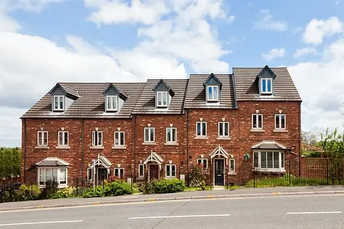 Row of charming, red-brick townhouses with white-trimmed windows and peaked roofs