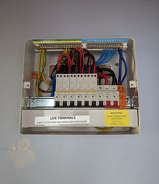 Electrical panel with multiple circuit breakers, labeled wires, and warning signs