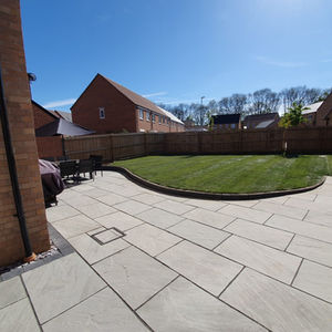 Sunny backyard with a large stone patio