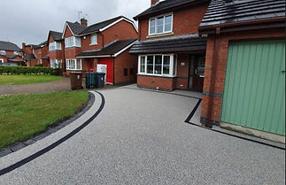 a modern gray and black lined driveway leading to a mint green garage door