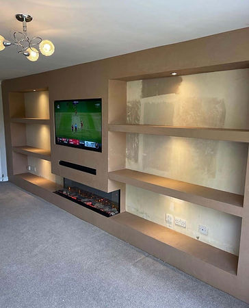 Modern living room with built-in shelves, a wall-mounted TV showing a cricket game