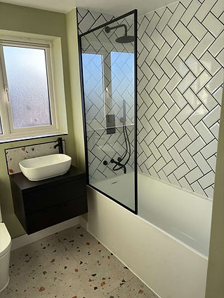modern bathroom featuring a white bathtub, black-framed shower screen