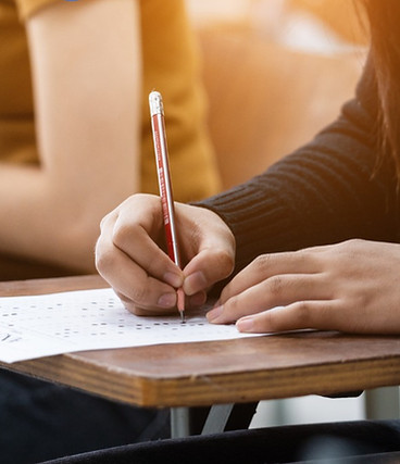 Students seated at desks taking exams, focusing intently
