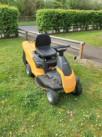 A yellow ride-on lawnmower on a grass lawn