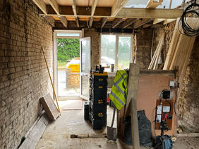 Internal renovation of a building showing exposed brick walls, bare ceiling joists