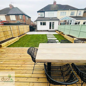 A long backyard view from an elevated timber deck with an outdoor dining table