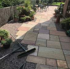 A sunlit garden path with multicolored stone tiles