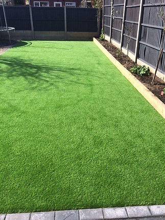 Vibrant green artificial grass lawn bordered by black fences