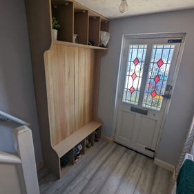 Entrance hallway featuring light grey wood-effect flooring, a large wooden hallway storage unit