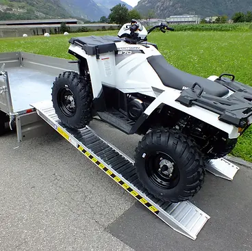 A white ATV with large black tires is mounted on metal ramps