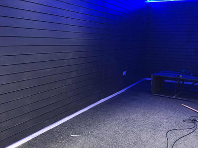 A dimly lit room with dark paneled walls and blue LED lighting