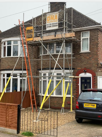A brick house with scaffolding supporting the porch roof