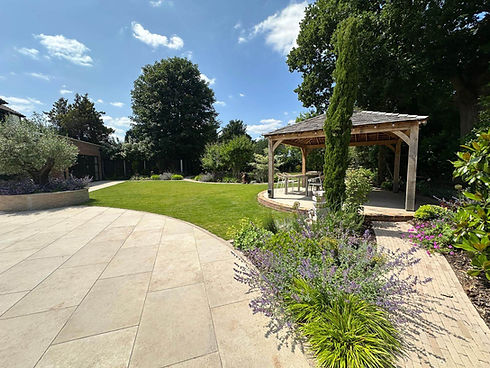 Sunny garden with a stone patio, lush green lawn