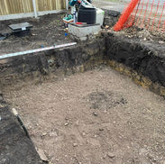 Excavation site showing a deep trench, gravel base