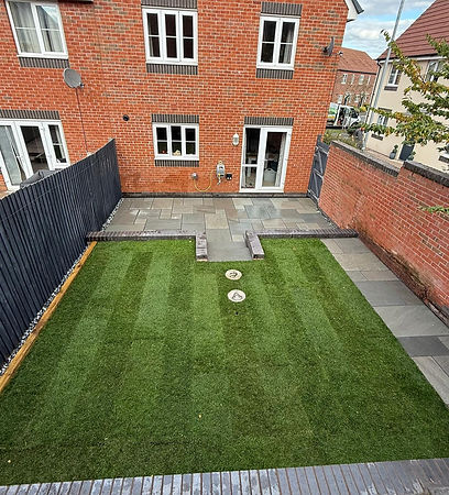 Backyard of a red-brick house with a neat, striped lawn and paved patio