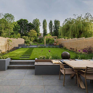 A modern backyard garden with a wooden dining set on a tiled patio