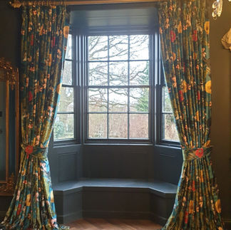 Bold floral curtains surrounding a curved bay window in a classic room