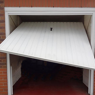 White garage door partially open, slanted on one side