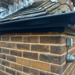 Red-brick house corner with new black gutter