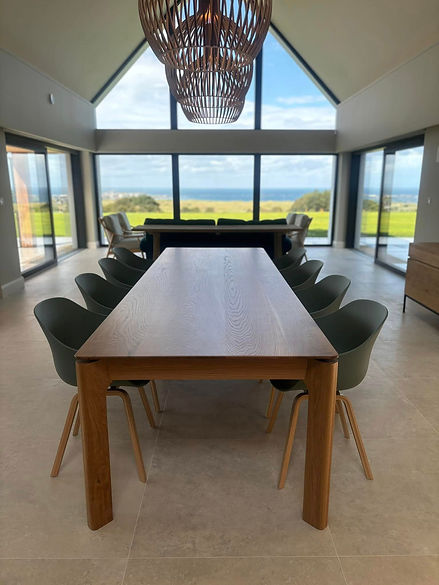 Long wooden dining table with green chairs in a bright room