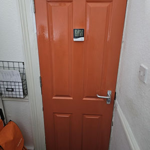 Red wooden panelled flat door featuring a gold-coloured number 5 positioned above a silver lever handle and lock
