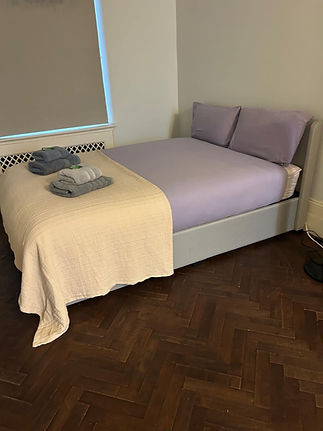 A neatly made bed with light purple sheets and two pillows
