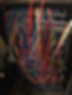 A tangled network of red, blue, and yellow cables connecting various server units