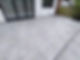 Modern patio with large gray tiles, adjacent to a white house