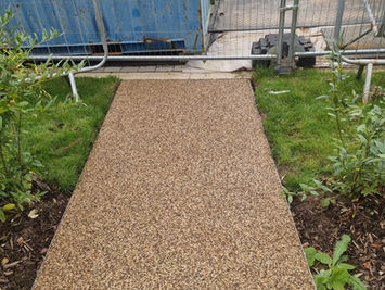 A resin-bound gravel path leading up to a residential patio with outdoor seating