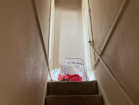 A narrow, straight staircase with brown carpeting