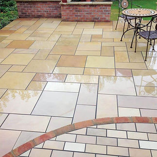 Wet sandstone patio with interlocking tan and beige tiles