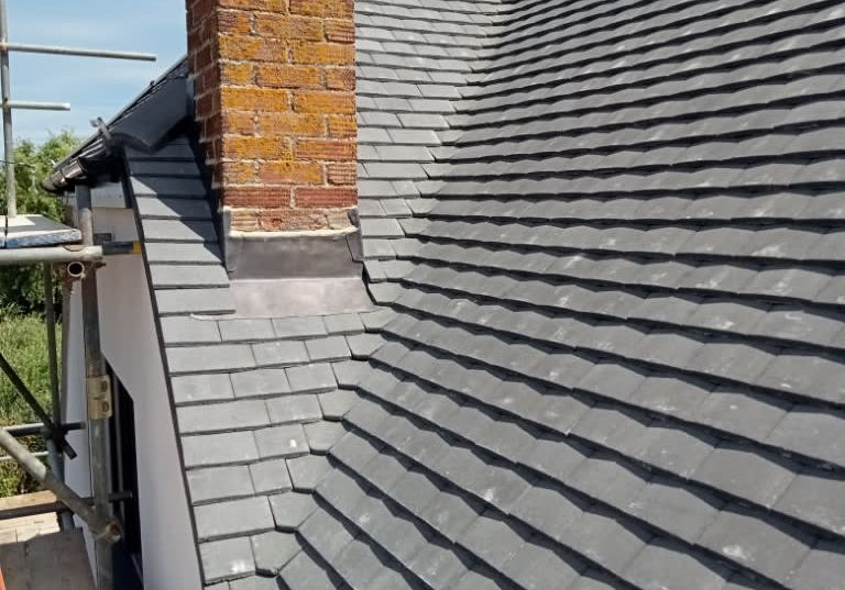 A view of a sloped gray roof with a brick chimney.