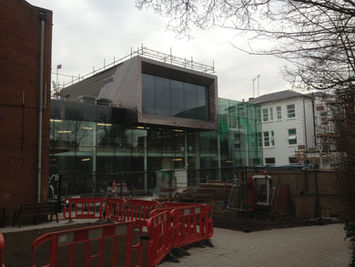 A modern school building under construction with a large glass facade