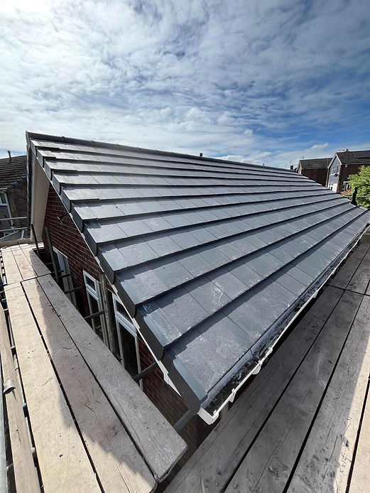 Gray slate tiles cover a pitched roof, set against a clear sky