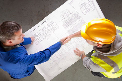 Two men, one in a blue jacket and the other in a yellow hard hat and vest, shake hands over a large architectural blueprint