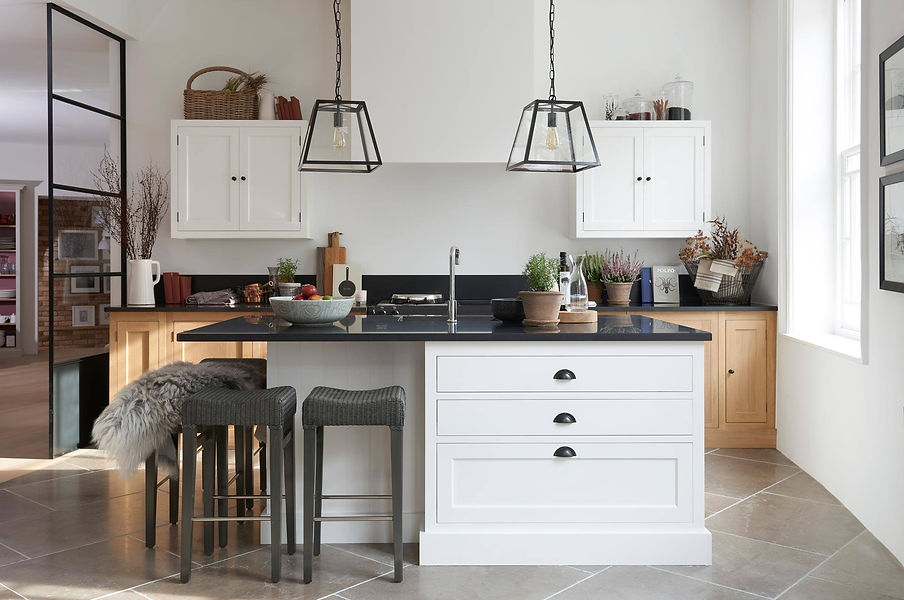 A grey kitchen island with a black worktop and wooden stools in a bright, modern kitchen