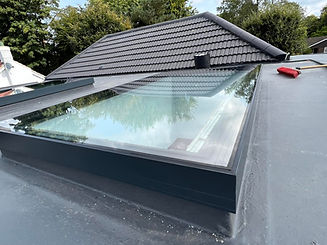 Exterior view of a dark grey tiled roof with a large integrated rectangular skylight