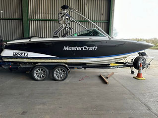 A black and white MasterCraft boat on a trailer, parked indoors