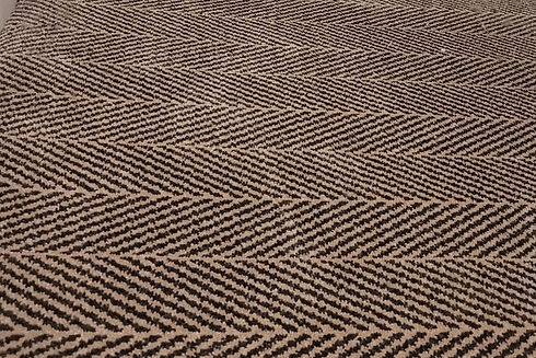 A close-up shot of a textured woven carpet with a distinctive brown and black chevron pattern