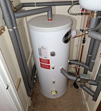 Modern hot water cylinder with pipework in a utility space