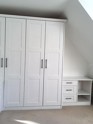 White wardrobe with four doors, next to an adjoining white unit with three drawers