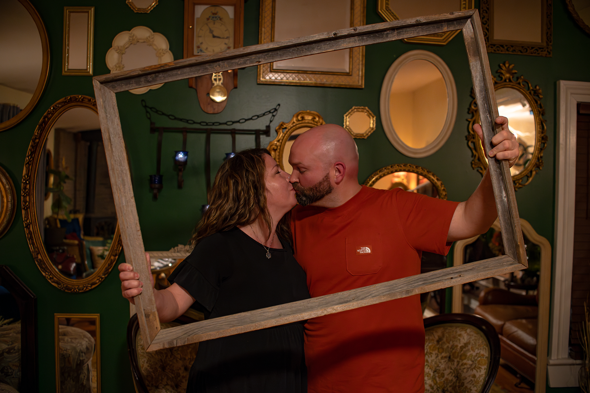 photo of dinner guest couple kissing, holdingn a picture frame to frame themselves