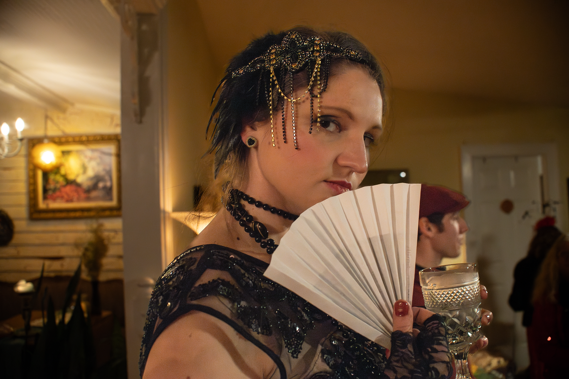 branding photo for The Whistlestop Manor , photo of guest dressed in 1920's attire, holding a paper fan up to her face