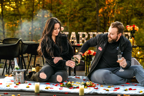 man pouring fiance champagne in front of marry me letters after he proposed