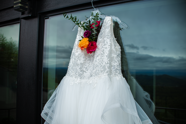 wedding dress hanging on window with cloudy sky and Smoky Mountain reflection