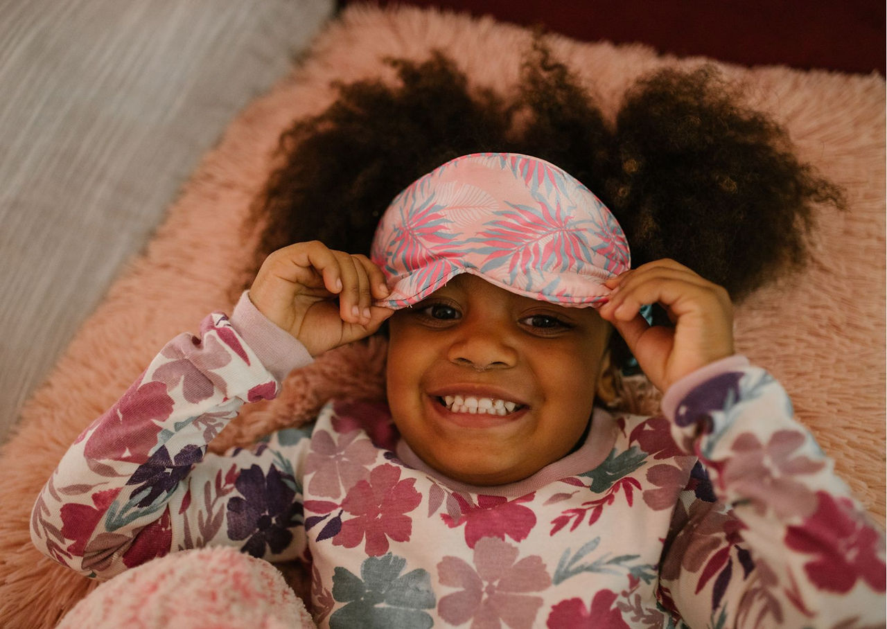 menina negra cabelo cacheados com tapa olho e pijama