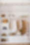Wardrobe with clothes in beige, brown and light shades on the hangers and things in contai