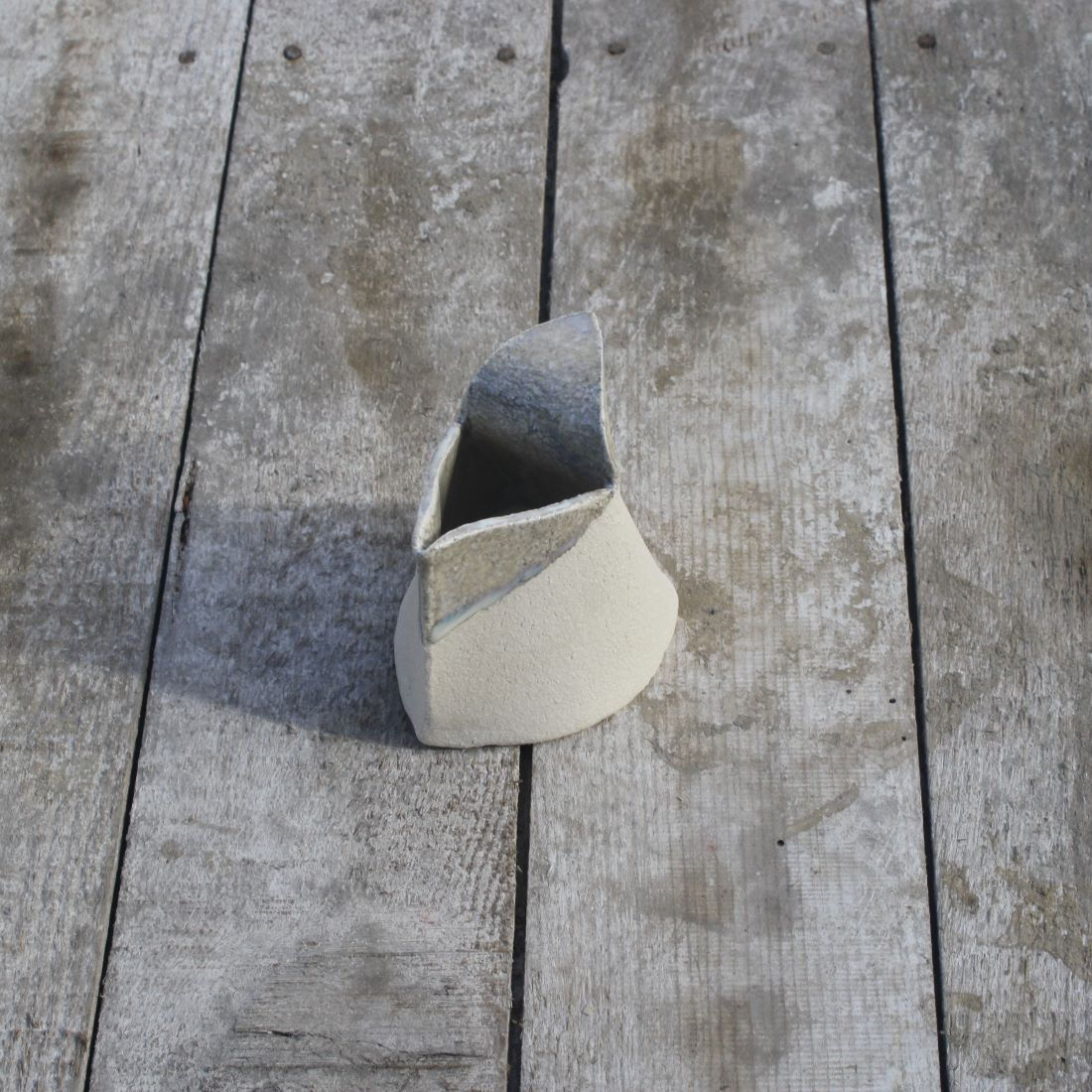 Saucier/crémier artisanal en grès blanc émail clair à cristallisations posé sur table en bois vue de 3/4 face