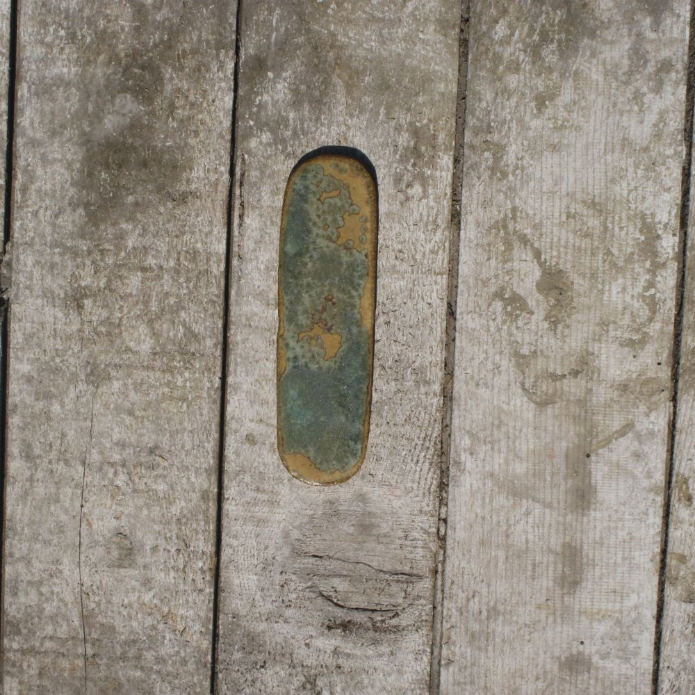 Porte-couteau artisanal en grès moucheté jaune moutarde/vert/turquoise posé sur table en bois vue du dessus